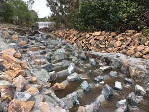 Completed rock-ramp fishway during first flow event following construction. Image shows the ‘blanked’ out ridge slots along the entire left side of the fishway, providing ample resting zones free of flow turbulence for migrating fish ascending the fishway.