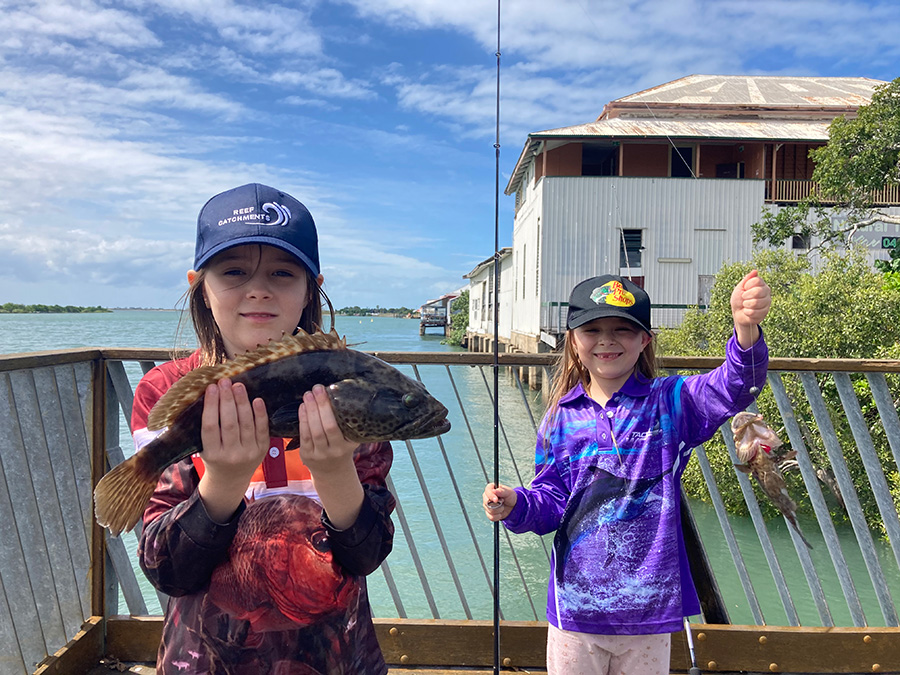 Recreational fishers, young girls, catching estuary cod fishing on artificial reef Bommie Modules in a Queensland estuary, Australia 